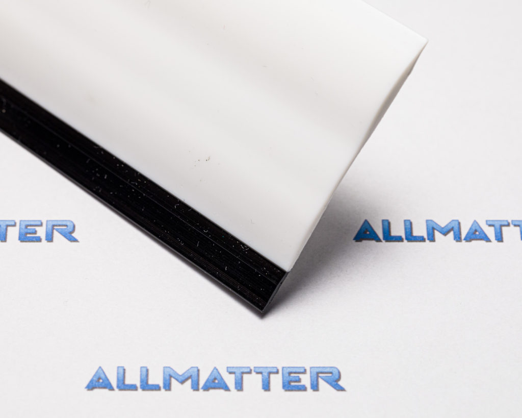 Biały element z czarną podstawą na tle logo Allmatter