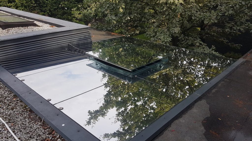 Przeszklony dach odbijający otaczającą zieleń i niebo