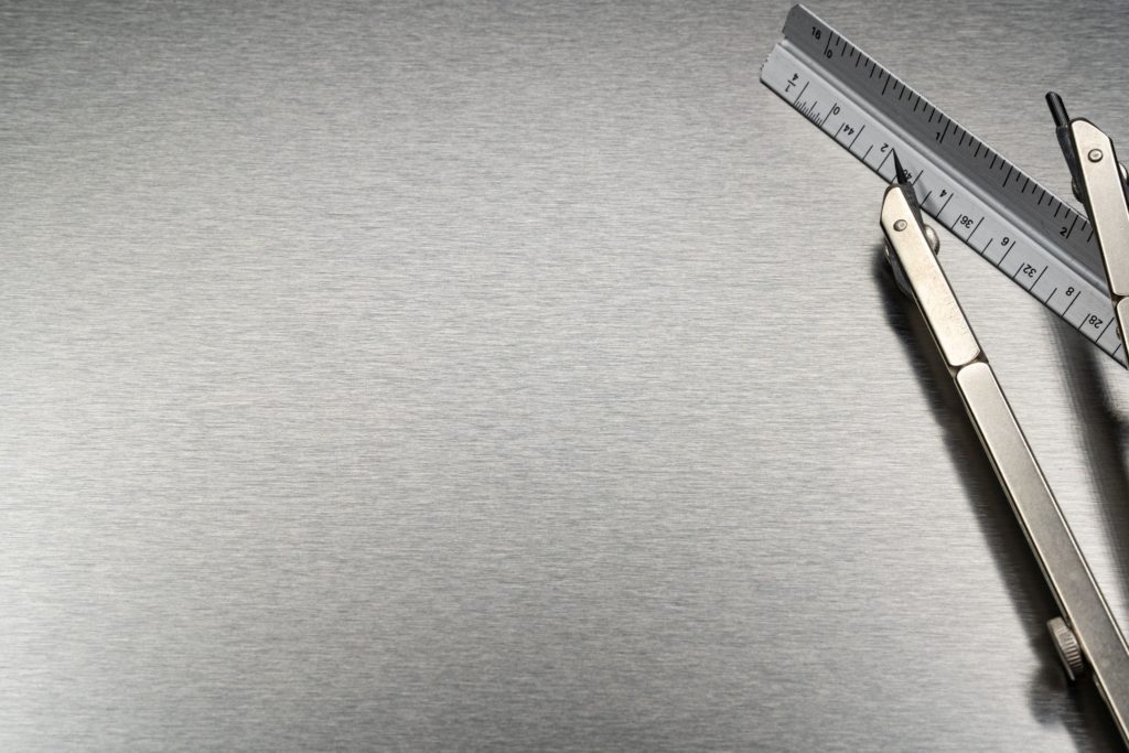 Srebrna folia metalowa z przyrządami kreślarskimi w rogu zdjęcia